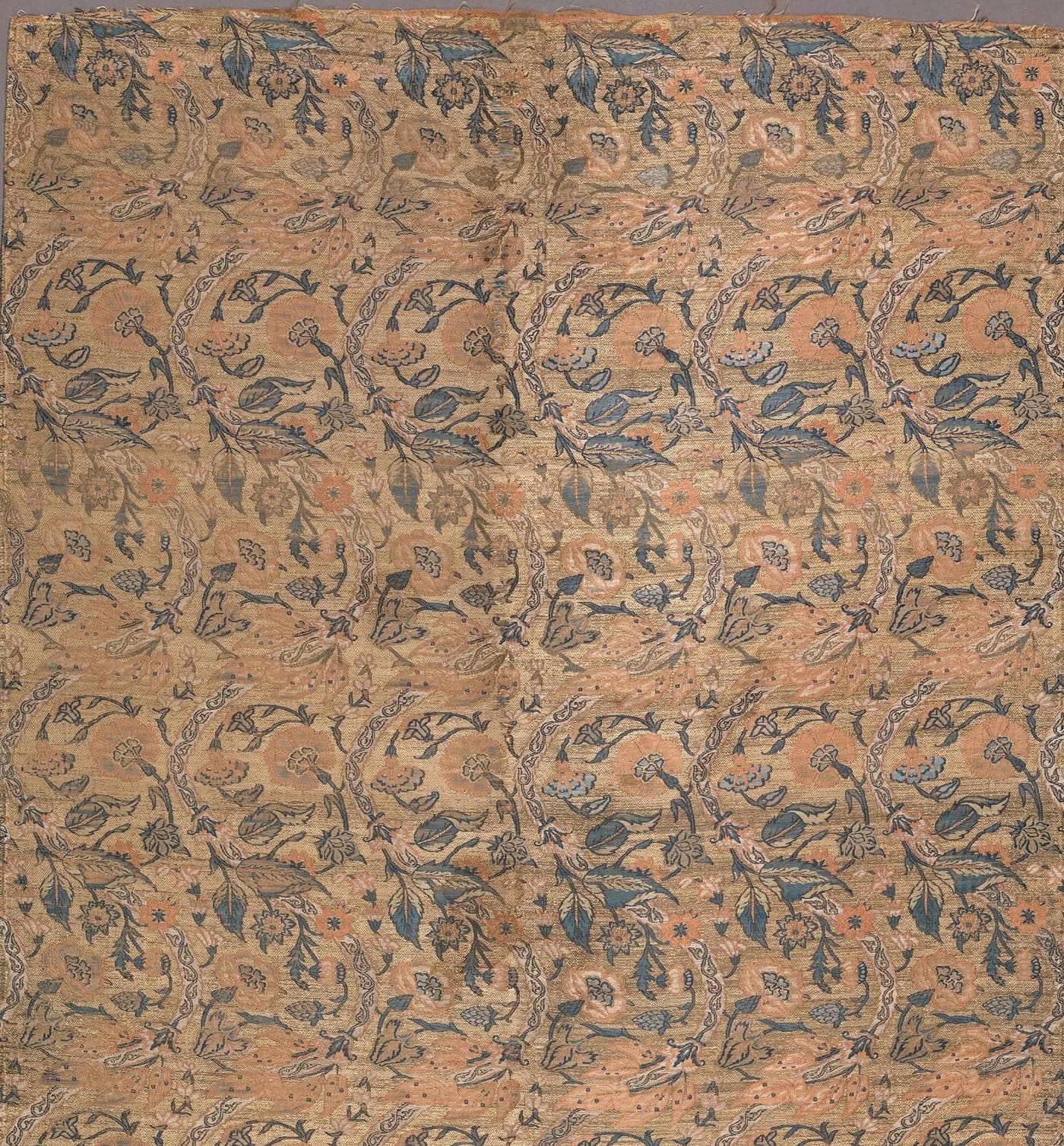 Faded rose silk covered in a fine trailing paisley vine in indigo and gold