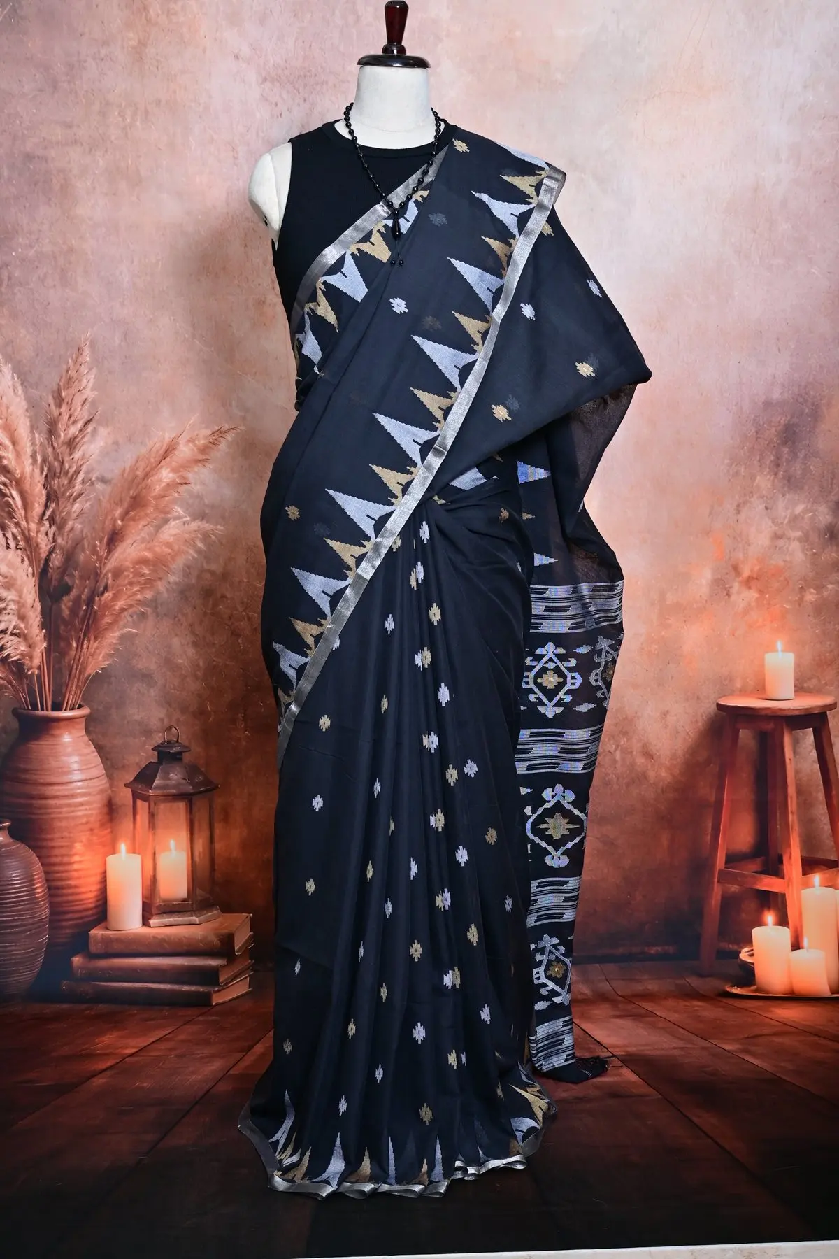 Pleats of a black cotton saree with small silver and gold motifs, next to a pallu with silver diamond patterns and stripes.