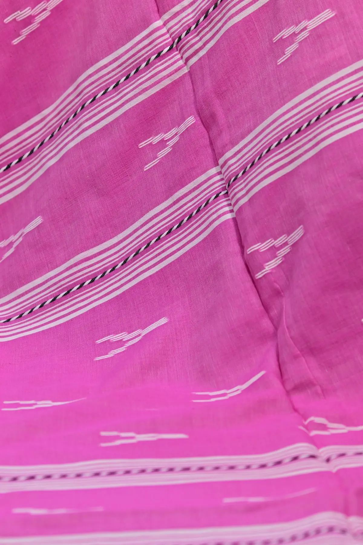 Pink saree fabric gathered in soft folds, showing white stripe bands and small white motifs.