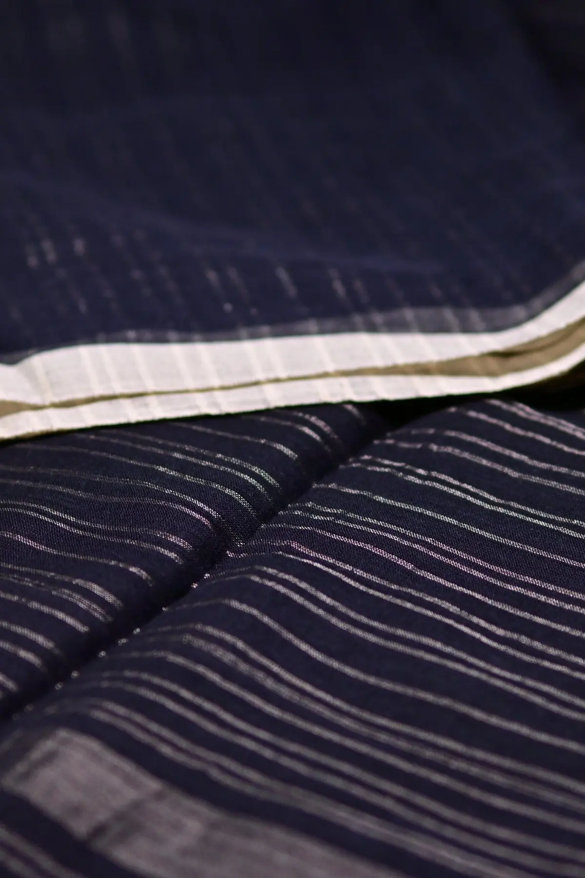 Navy saree fabric swirled to show fine silver-toned stripes.