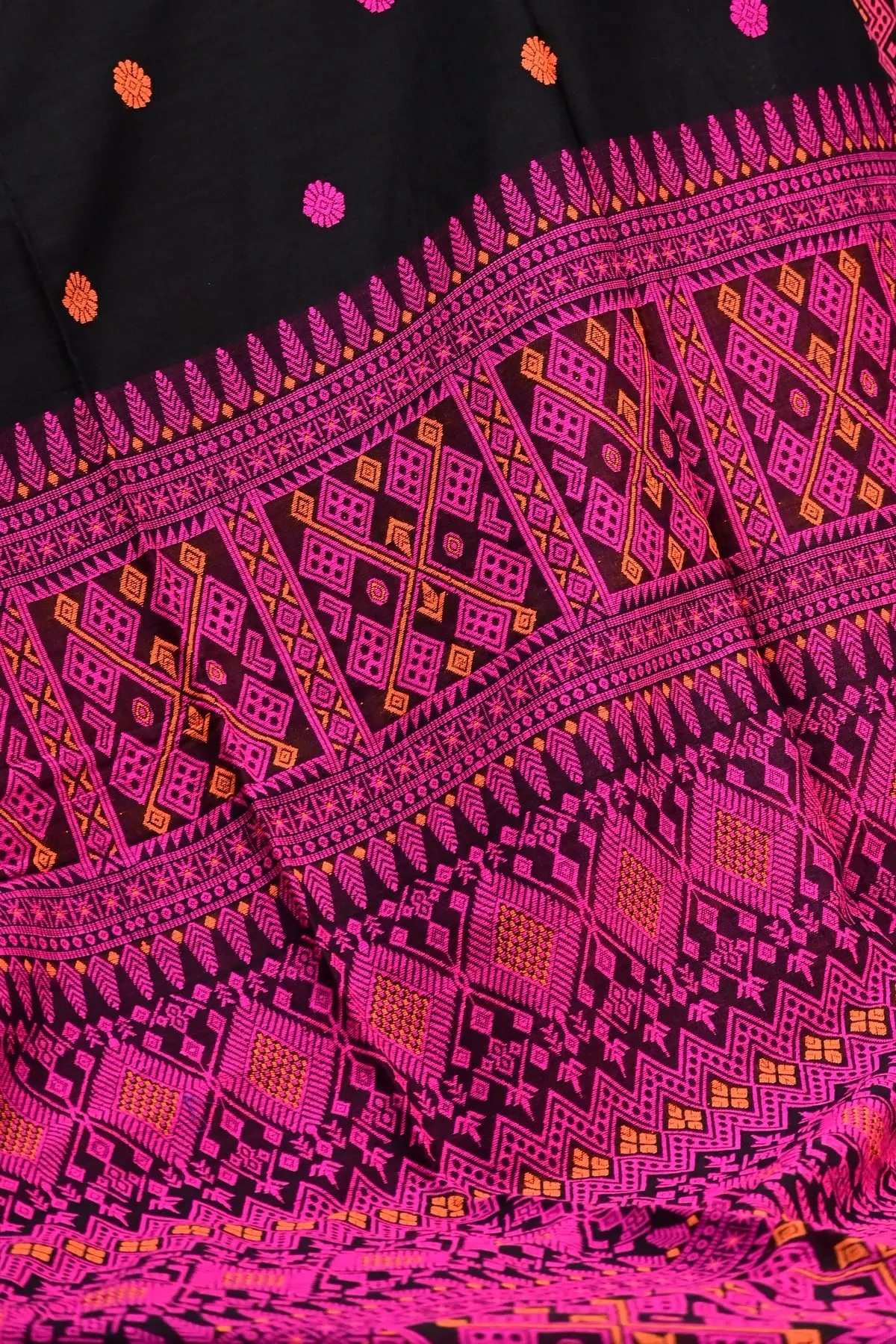 Black saree with a folded pink geometric border laid over a pink, black and orange patterned pallu.