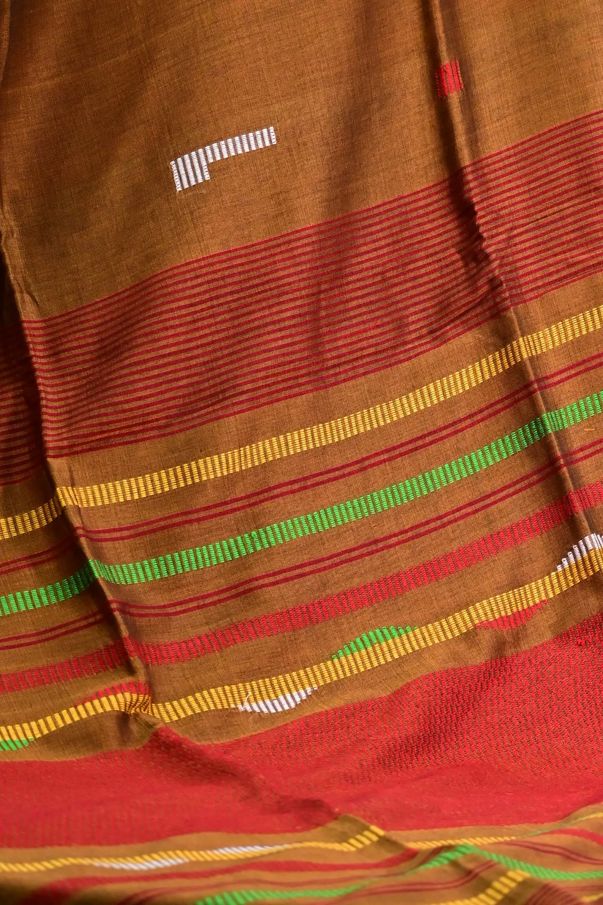 Mustard-brown saree swirled with its red, yellow and green striped pallu.