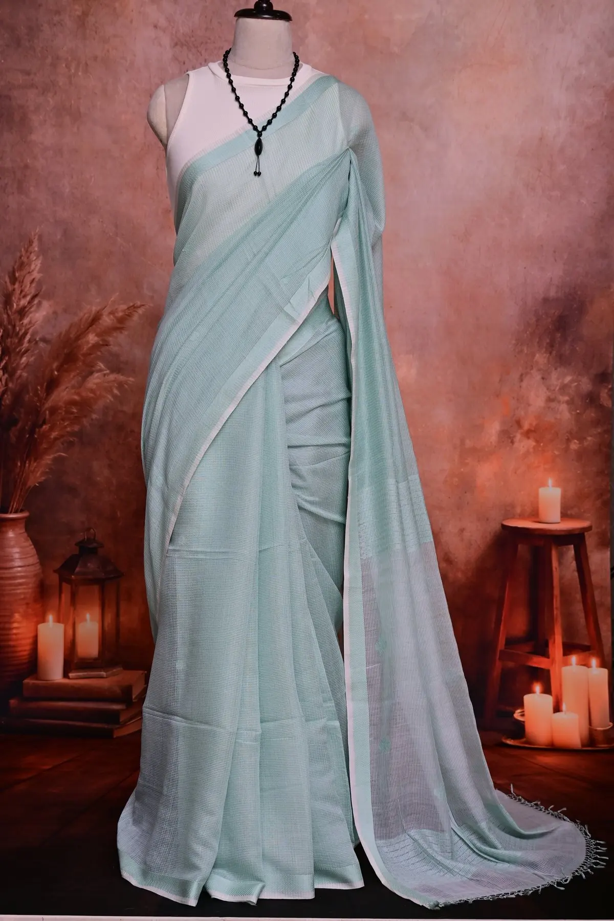 Mint checked saree draped in folds, with a narrow white border crossing the front.