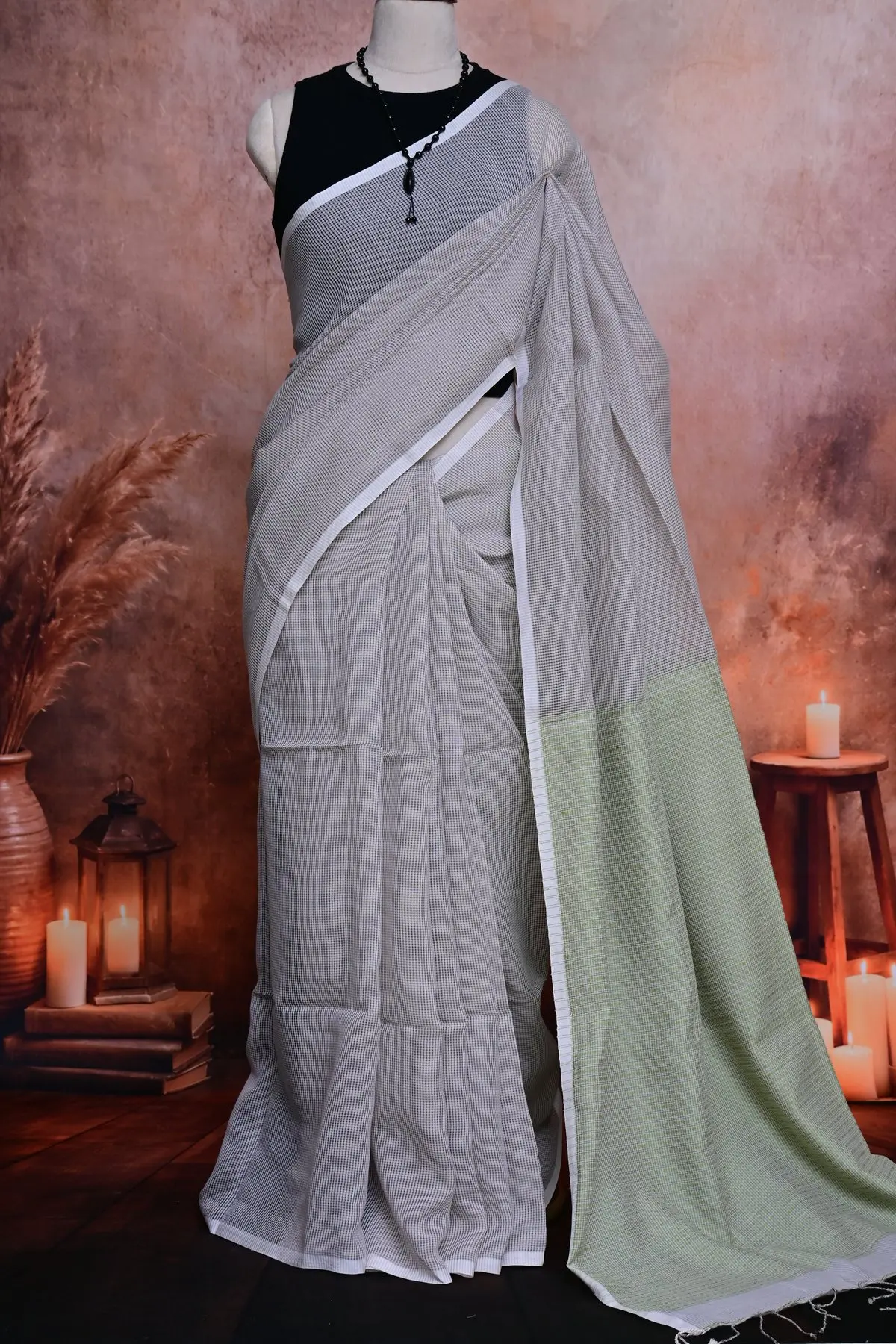 Grey checked saree in pleats with the green pallu hanging alongside.