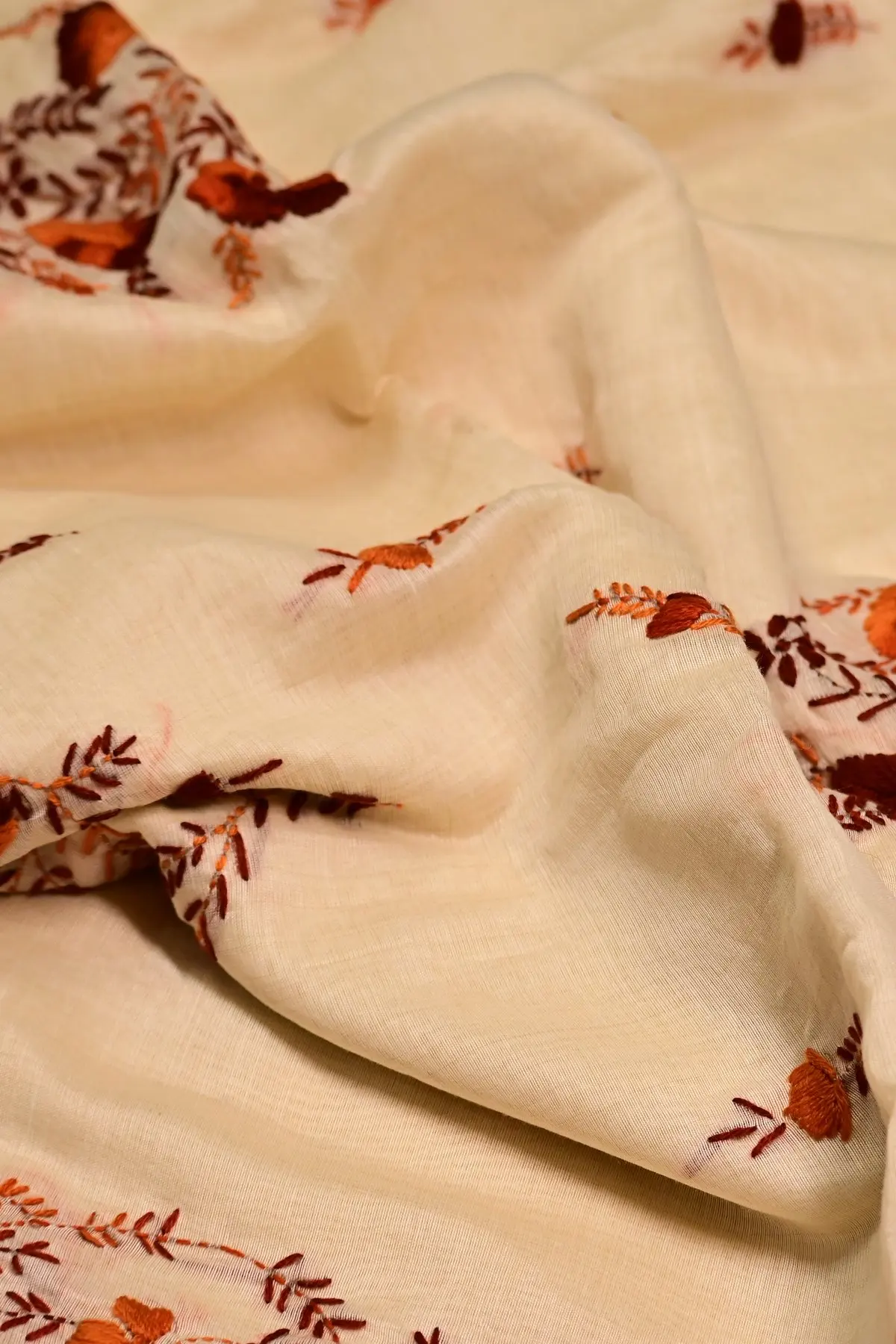 Cream saree with rust and maroon floral embroidery, texture