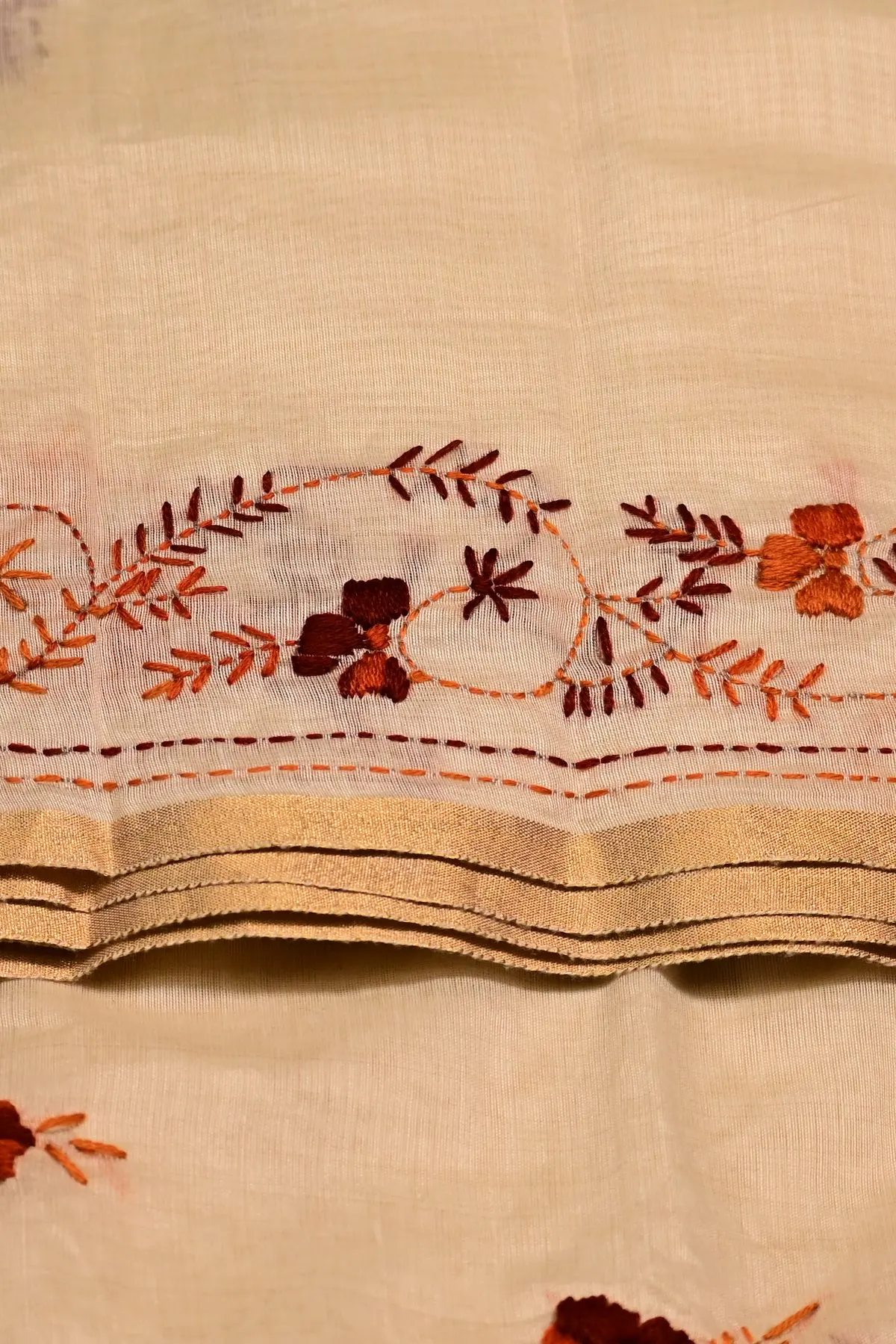 Cream saree with rust and maroon floral embroidery, border